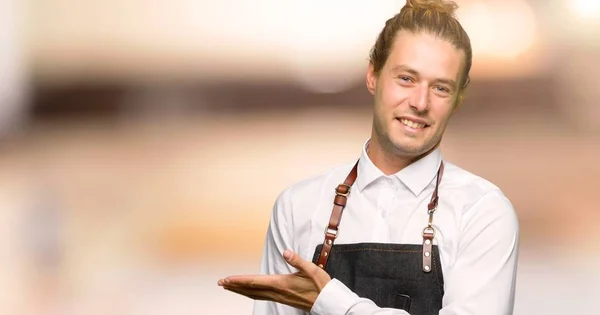 Barber man in an apron presenting an idea while looking smiling towards in a barber shop