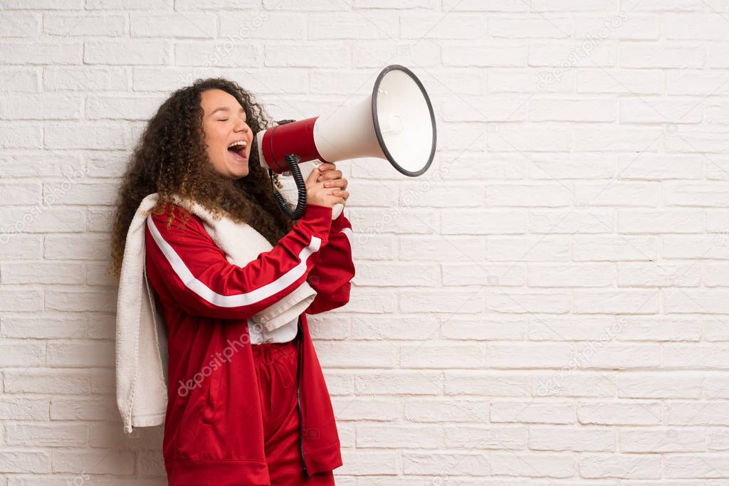 Teenager sport girl with curly hair shouting through a megaphone