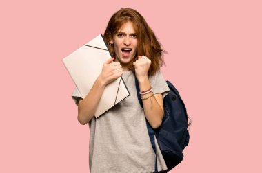 Pembe bir arka plan üzerinde kötü bir durum tarafından hayal kırıklığına uğramış genç redhead öğrenci