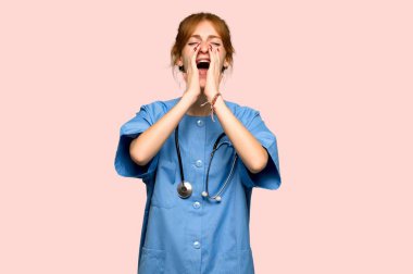 Bağırarak ve bir şey üzerinde pembe arka plan duyuran genç redhead hemşire