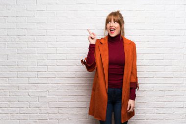 Parmak kaldırma sırasında çözüm isteyen beyaz tuğla duvarın üzerinden montlu kadın anlar