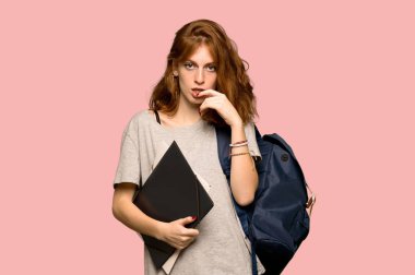 Pembe arka plan üzerinde ararken şüpheleri genç redhead öğrenci