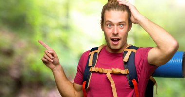 Parmak tarafına işaret ve dağ bir ürün sunan dağ backpacker adamla uzun yürüyüşe çıkan kimse