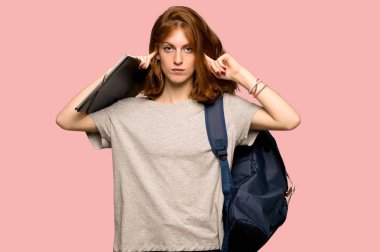 Her iki kulak elleriyle pembe arka plan üzerinde kapsayan genç redhead öğrenci