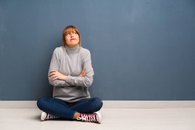 Kızıl saçlı kadın açık kat yapma siting jest omuz kaldırma sırasında şüpheler