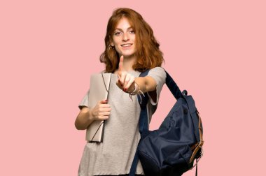 Gösterilen ve pembe arka plan üzerinde parmak kaldırma genç redhead öğrenci