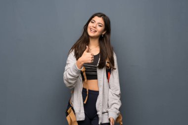 Genç Gezgin kız jest Yaşasın vererek ve gülümseyen duvarın üzerinden