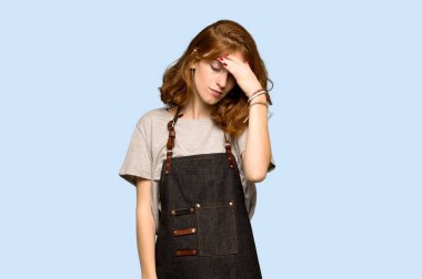 Önlük ile mavi arka plan üzerinde yorgun ifade ile genç Kızıl saçlı kadın