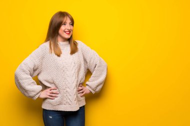 Kızıl saçlı kadın kalça, silah ile poz ve gülümseyen sarı duvarın üzerinden