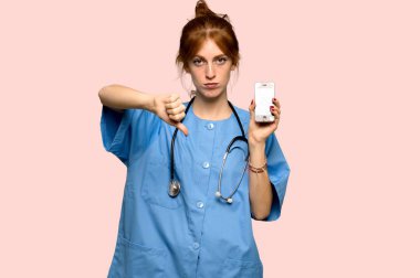 Genç redhead hemşire pembe bir arka plan üzerinde kırık telefon ile