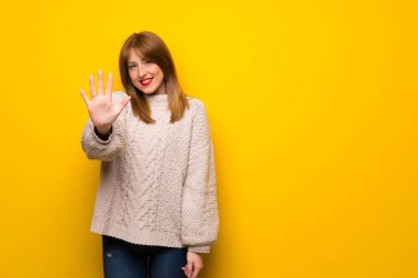 Kızıl saçlı kadın beş parmak ile sayma sarı duvarın üzerinden