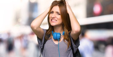 Kızıl saçlı öğrenci kadın alır eller başının üstüne çünkü şehirde migren vardır