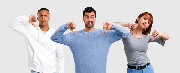 Groep van drie vrienden tonen duim omlaag bord met negatieve exp — Stockfoto