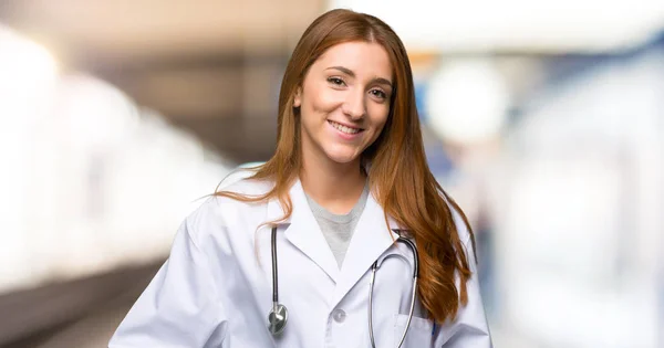 Rossa Medico Donna Posa Con Braccia All Anca Sorridente Ospedale — Foto Stock