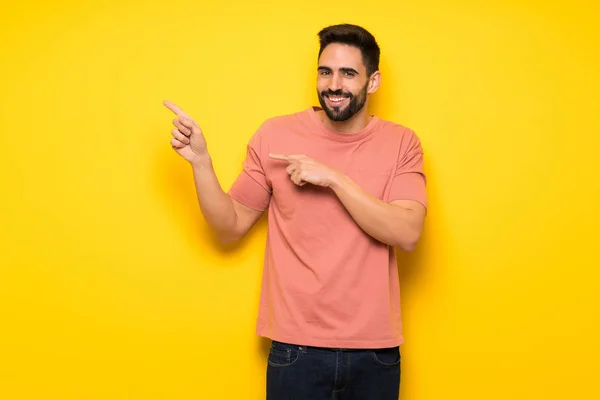 Bonito Homem Sobre Parede Amarela Apontando Dedo Para Lado Posição — Fotografia de Stock