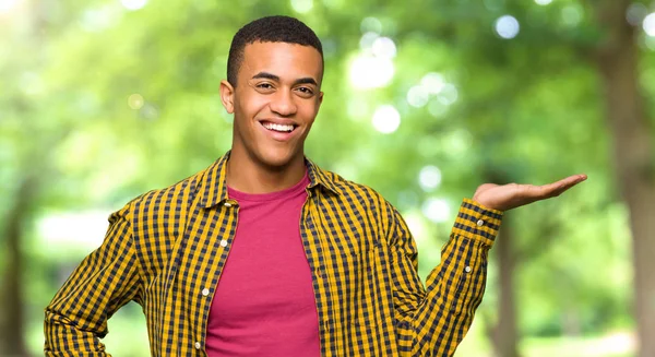 Young Afro American Man Holding Copyspace Imaginary Palm Insert Park — Stock Photo, Image