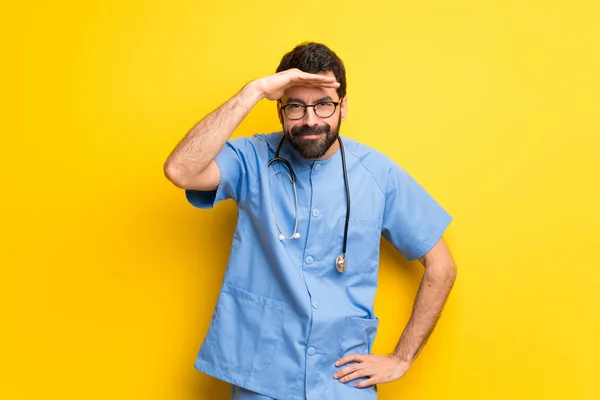 Surgeon doctor man looking far away with hand to look something