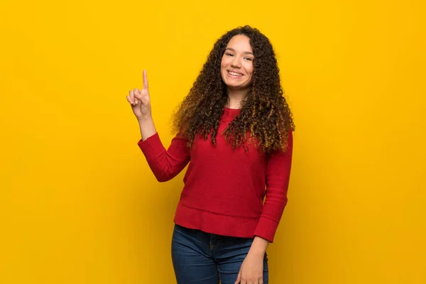 Adolescente Chica Con Suéter Rojo Sobre Pared Amarilla Mostrando Levantando —  Fotos de Stock
