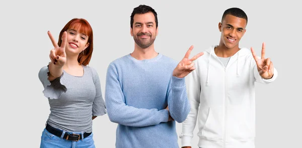 Grupo de tres amigos sonriendo y mostrando señal de victoria — Foto de Stock