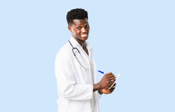 Medico afroamericano che tiene un quaderno sulla schiena blu isolata — Foto Stock
