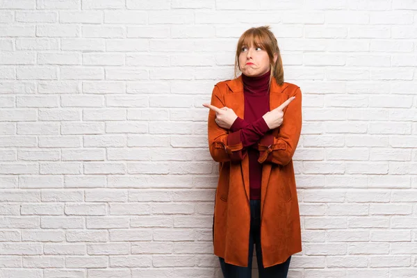 Femme Avec Manteau Sur Mur Briques Blanches Pointant Vers Les — Photo