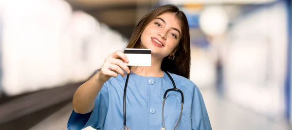 Young nurse holding a credit card in a hospital