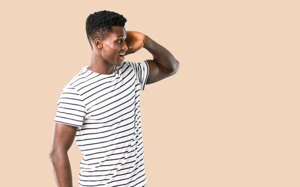 Hombre de piel oscura con camisa a rayas escuchando algo en isola — Foto de Stock