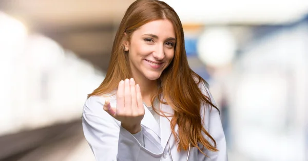 Redhead doctor woman inviting to come with hand. Happy that you came in the hospital