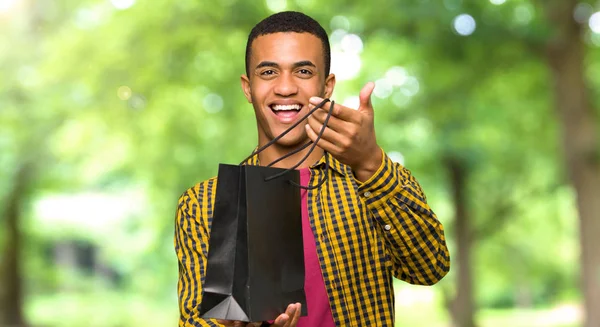 Bir Sürü Alışveriş Torbaları Bir Parkta Tutan Genç Afro Amerikalı — Stok fotoğraf