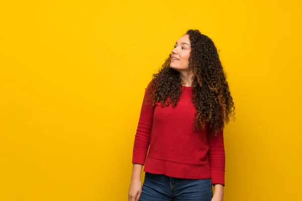Девочка-подросток в красном свитере на желтой стене — стоковое фото