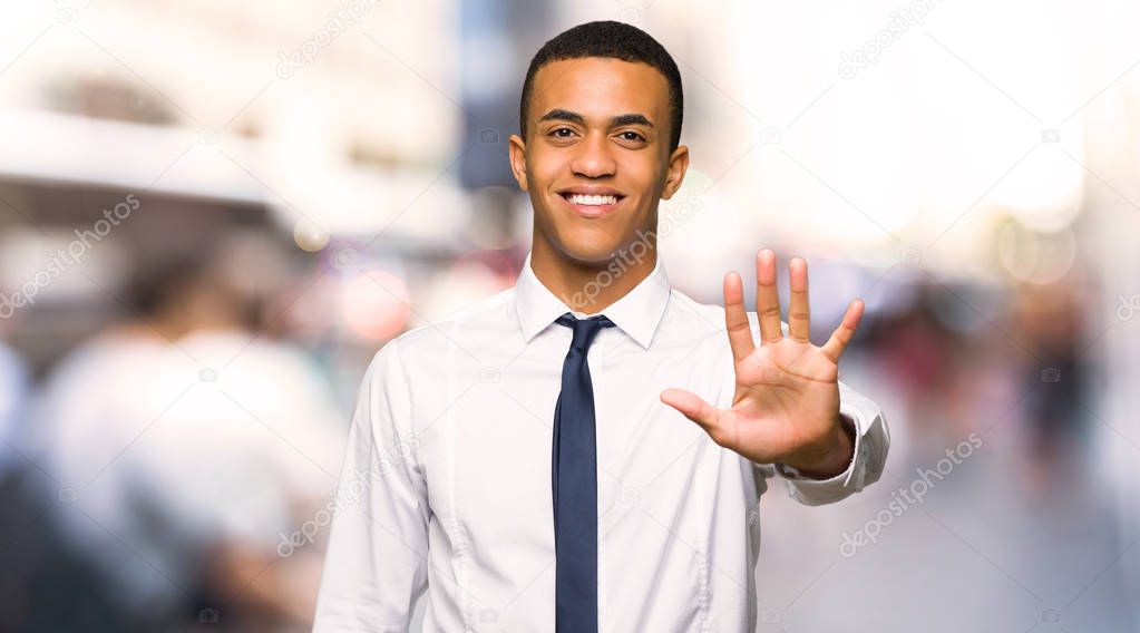 Young afro american businessman counting five with fingers in the city