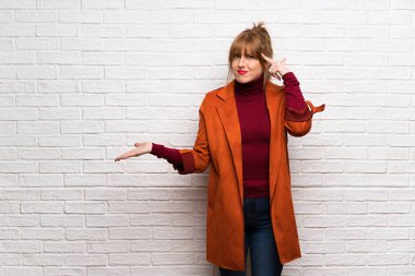 Kat parmak kafasına koyarak delilik jest yapma beyaz tuğla duvarın üzerinden kadınla