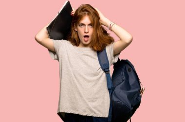 Genç redhead öğrenci alır eller başının üstüne çünkü pembe arka plan üzerinde migren vardır