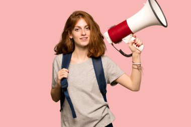 Bir megafon pembe arka plan üzerinde tutan genç redhead öğrenci