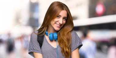 Kızıl saçlı öğrenci kadın mutlu ve gülümseyerek şehir