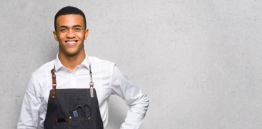 Silah, kalça ile poz ve dokulu duvar üzerinde gülümseyen genç afro Amerikan Kuaför adam