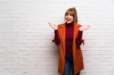 Kat şok yüz ifadesi ile beyaz tuğla duvarın üzerinden kadınla