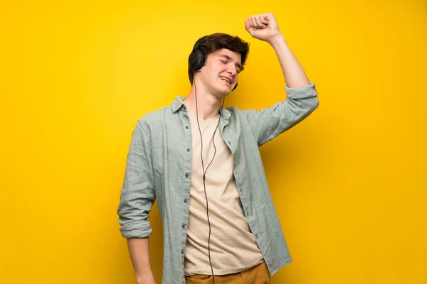 Adolescente Homem Sobre Parede Amarela Ouvindo Música Com Fones Ouvido — Fotografia de Stock