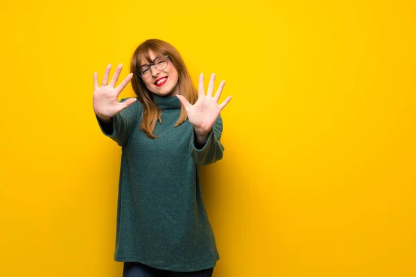Parmak Ile Sayma Sarı Duvarın Üzerinden Gözlüklü Kadın — Stok fotoğraf