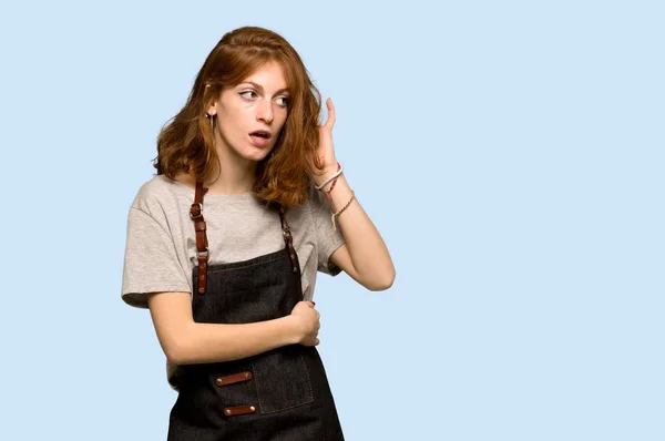 Young Redhead Woman Apron Listening Something Putting Hand Ear Blue — Stock Photo, Image