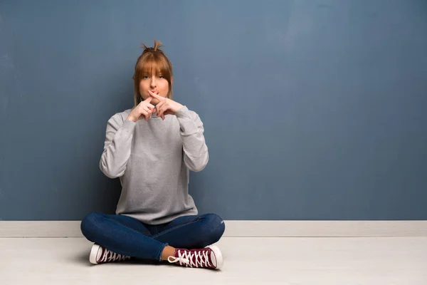 Rothaarige Frau Sitzt Auf Dem Boden Und Zeigt Ein Zeichen — Stockfoto