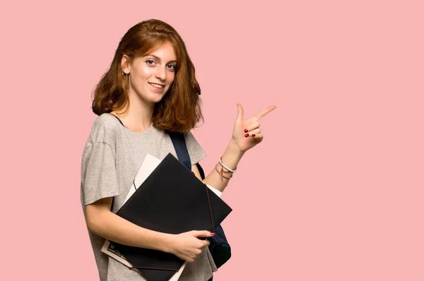 Junge Rothaarige Studentin Zeigt Mit Dem Finger Seitlich Auf Rosa — Stockfoto