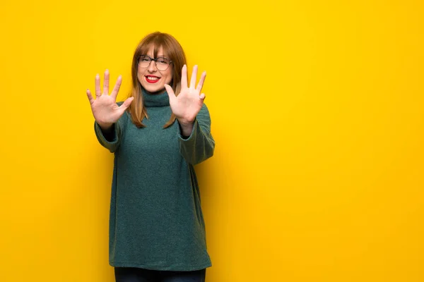 黄色の壁を指で カウントで眼鏡を持つ女性 — ストック写真
