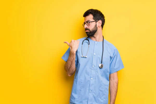 Surgeon doctor man unhappy and pointing to the side