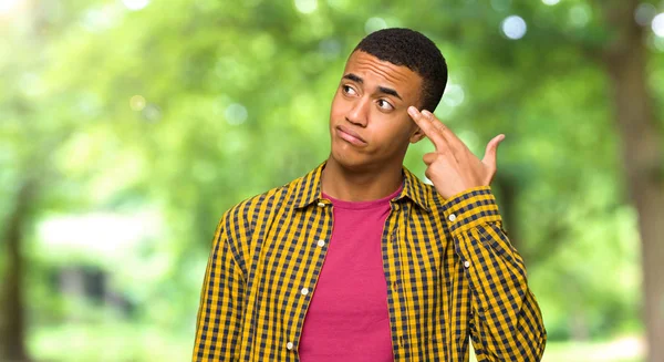 Young afro american man with problems making suicide gesture in a park