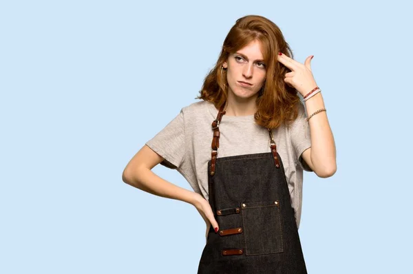 自殺の問題とエプロンの若い赤毛の女性青い背景上のジェスチャー — ストック写真
