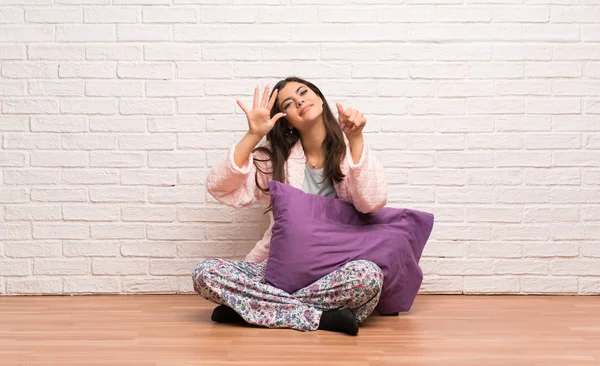 Teenager girl in pajamas counting six with fingers