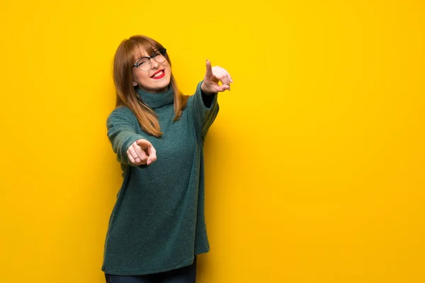 Vrouw Met Bril Gele Muur Points Vinger Bij Terwijl Het — Stockfoto