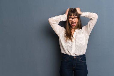 Sürpriz ve şok yüz ifadesi ile mavi duvarın üzerinden gözlüklü kadın