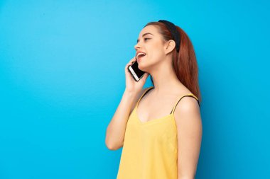 Cep telefonu ile bir konuşma tutmak mavi arka plan genç Kızıl saçlı kadın